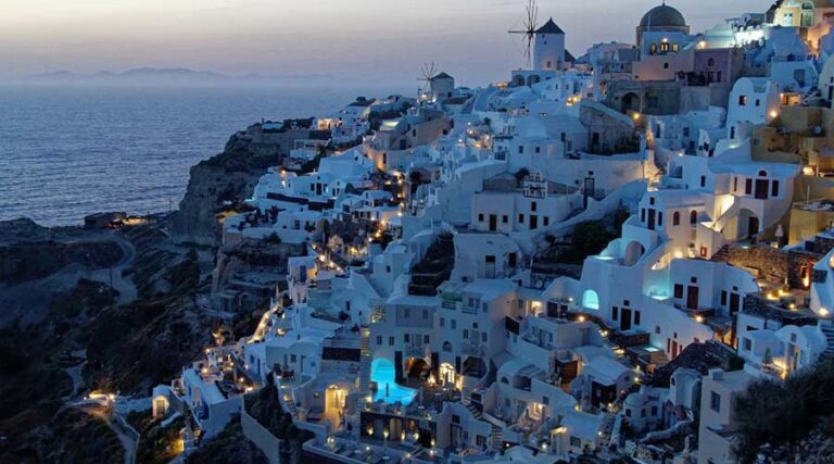 Blick auf ein griechisches Dorf am Hang eines langgestreckten Hügels. Die Häuser sind weiß und erinnern auch an die Häuser auf Santorini.